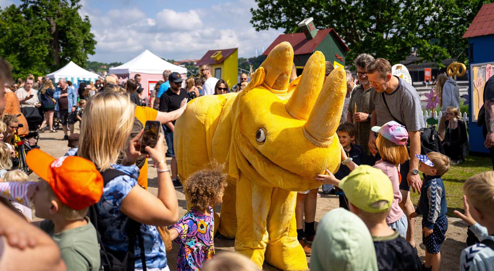 Børn og voksne flokkes omkring en stort, gult næsehorn i festivalområdet til Sløngeldagene i Skanderborg.